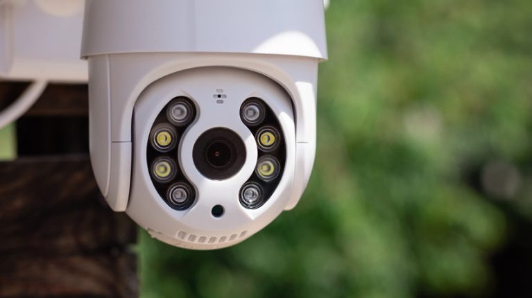 IP CCTV wifi surveillance camera on backyard background. Concept of home security technology. vertical image